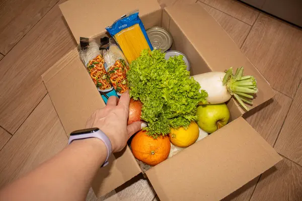 Bir kadının eli bir market kutusunu bağış ile açar.