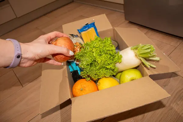 Gönüllü bir kadın kutular dolusu yiyecek bağışında bulunuyor.