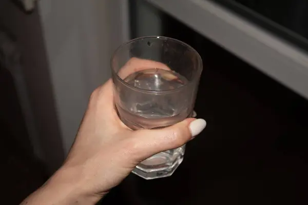 Bir kadının elinde bir bardak saf su.