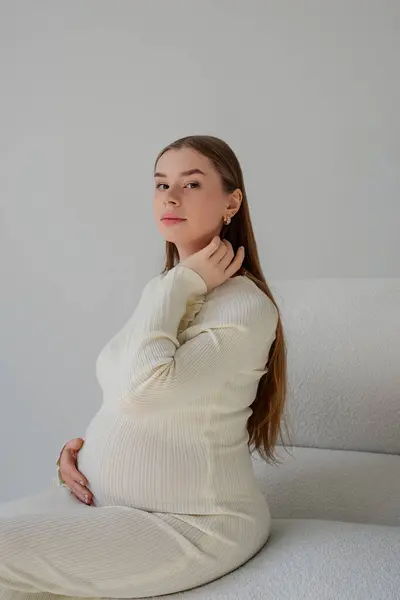 Güzel bir genç kız koltukta oturuyor ve saçını düzeltiyor.