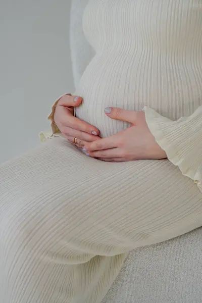 Hamile genç anne karnını okşuyor.