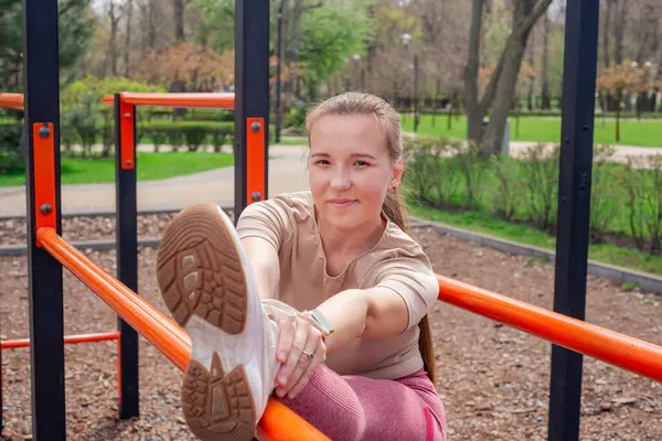 Genç bir kadın spor salonunda bacak ve kol hareketleri yapıyor, spor kıyafetler giyiyor, bahar havasında aktif ve sağlıklı kalıyor..