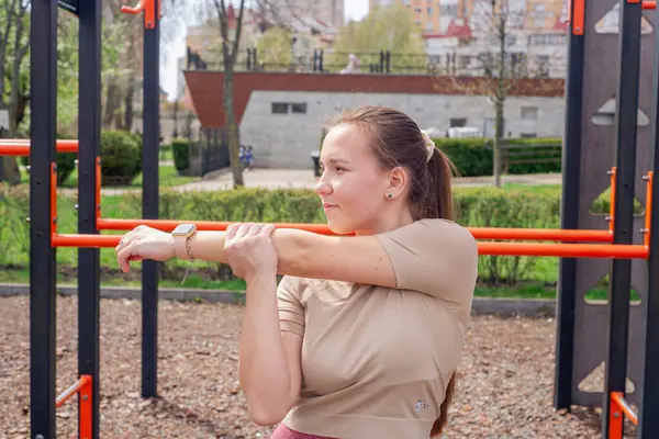 Genç bir kadın spor salonunda bacak ve kol hareketleri yapıyor, spor kıyafetler giyiyor, bahar havasında aktif ve sağlıklı kalıyor..