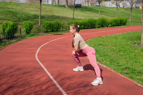 Genç bir kadın spor salonunda bacak ve kol hareketleri yapıyor, spor kıyafetler giyiyor, bahar havasında aktif ve sağlıklı kalıyor..