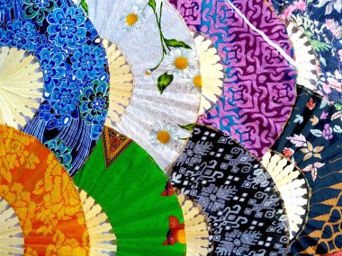 Kipas Tangan Motif Batik veya el yelpazesi Batik bambu ve batik kumaştan yapılmıştır. Batik desenli el vantilatörü beyaz arka planda izole edilmiş. Bali Endonezya 'dan el yelpazesi
