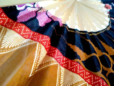 Kipas Tangan Motif Batik veya el yelpazesi Batik bambu ve batik kumaştan yapılmıştır. Batik desenli el vantilatörü beyaz arka planda izole edilmiş. Bali Endonezya 'dan el yelpazesi