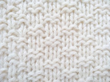 Yün ipliğinden örülmüş giysiler. İplik çerçevesi için yün iplik arkaplanı. El sanatları geçmişi için beyaz örgü ipliği