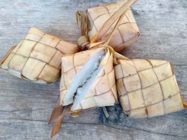 Tahta arka planda Tipat / Ketupat (Rice Dumpling). Ketupat, Bayram Bayramında, İdul Fitri / Aidilfitri 'de pilav pişirmek için genç hindistan cevizi yapraklarından yapılan doğal pirinç kabı.