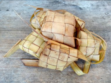 Tahta arka planda Tipat / Ketupat (Rice Dumpling). Ketupat, Bayram Bayramında, İdul Fitri / Aidilfitri 'de pilav pişirmek için genç hindistan cevizi yapraklarından yapılan doğal pirinç kabı.