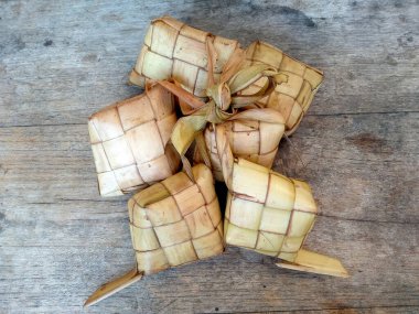 Tahta arka planda Tipat / Ketupat (Rice Dumpling). Ketupat, Bayram Bayramında, İdul Fitri / Aidilfitri 'de pilav pişirmek için genç hindistan cevizi yapraklarından yapılan doğal pirinç kabı.