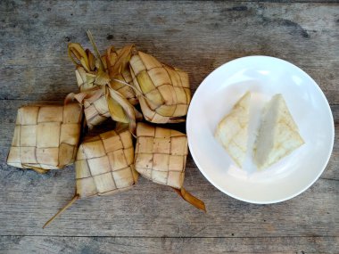 Tahta arka planda Tipat / Ketupat (Rice Dumpling). Ketupat, Bayram Bayramında, İdul Fitri / Aidilfitri 'de pilav pişirmek için genç hindistan cevizi yapraklarından yapılan doğal pirinç kabı.