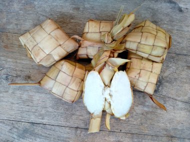 Tahta arka planda Tipat / Ketupat (Rice Dumpling). Ketupat, Bayram Bayramında, İdul Fitri / Aidilfitri 'de pilav pişirmek için genç hindistan cevizi yapraklarından yapılan doğal pirinç kabı.