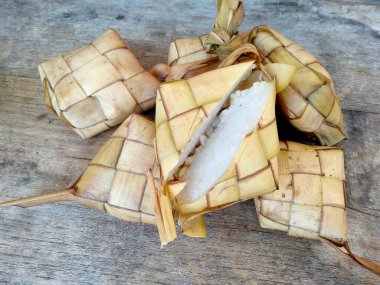 Tahta arka planda Tipat / Ketupat (Rice Dumpling). Ketupat, Bayram Bayramında, İdul Fitri / Aidilfitri 'de pilav pişirmek için genç hindistan cevizi yapraklarından yapılan doğal pirinç kabı.
