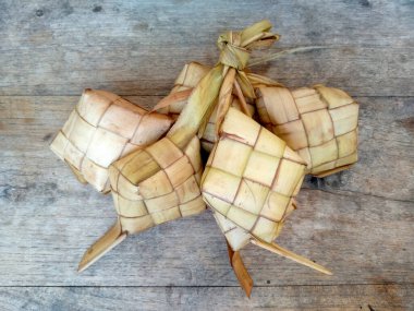 Tahta arka planda Tipat / Ketupat (Rice Dumpling). Ketupat, Bayram Bayramında, İdul Fitri / Aidilfitri 'de pilav pişirmek için genç hindistan cevizi yapraklarından yapılan doğal pirinç kabı.
