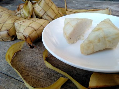 Tahta arka planda Tipat / Ketupat (Rice Dumpling). Ketupat, Bayram Bayramında, İdul Fitri / Aidilfitri 'de pilav pişirmek için genç hindistan cevizi yapraklarından yapılan doğal pirinç kabı.