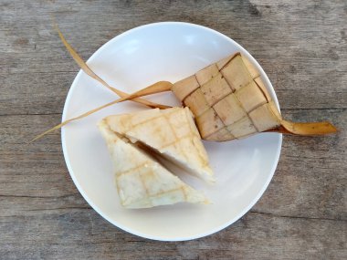 Tahta arka planda Tipat / Ketupat (Rice Dumpling). Ketupat, Bayram Bayramında, İdul Fitri / Aidilfitri 'de pilav pişirmek için genç hindistan cevizi yapraklarından yapılan doğal pirinç kabı.