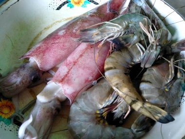 Balık pazarında taze mürekkep balığı ve karides. Tabak ve masada taze mürekkep balığı ve karides. Okyanustan, denizden, sahilden taze mürekkep balığı ve karides. (Cumi cumi cumi Segar Udang Segar )