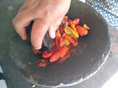 Geleneksel ev yapımı sambal ya da kırmızı acı biber ezmesi. Bir kase acı biber sosu izole edilmiş. Cobek taşı / Ulekan Batu 'da yapılan kırmızı biber sosu. Sambal Endonezya Gıda.