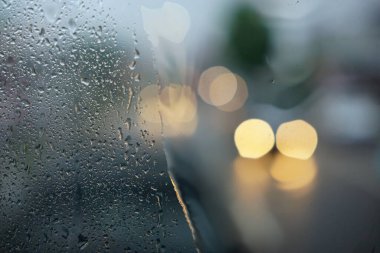 Raindrops on the windshield of the car with a bokeh light background. Focus selected