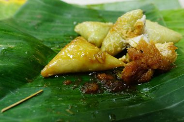 Lupis, a traditional cake from Java Indonesia. Made from rice, given grated coconut and brown sugar liquid. Served on banana leaves. Focus selected