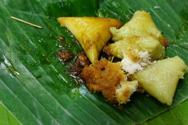 Lupis, a traditional cake from Java Indonesia. Made from rice, given grated coconut and brown sugar liquid. Served on banana leaves. Focus selected