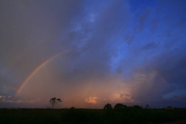 Bulutların ve mavi gökyüzünün arka planında gökkuşağı olan alacakaranlık.