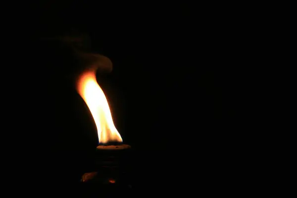 Siyah arka planda, gaz lambasında yanan bir ateş.
