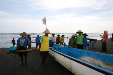 Balıkçılar tekneyi kıyıya çekmek için birlikte çalışıyorlar.
