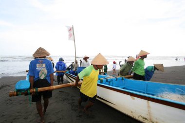 Balıkçılar tekneyi kıyıya çekmek için birlikte çalışıyorlar.