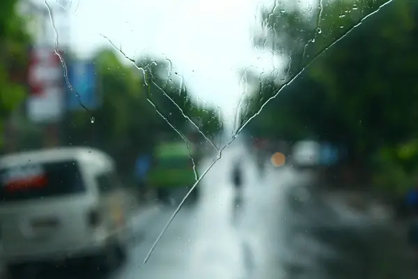 Arabanın ön camında yağmur damlaları var. Odaklanma seçildi. Bulanık arkaplan
