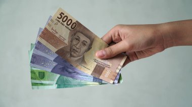 Endonezya rupiası, 5,000 rupiah, 10,000 rupiah, ve 20,000 rupiah, kadınların elinde.