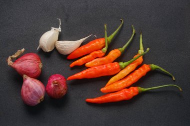 Kırmızı biber, arpacık soğanı ve siyah arka planda sarımsak.