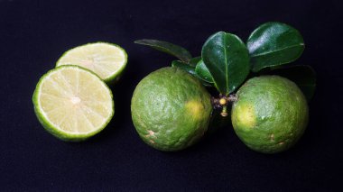 Kaffir limonu ya da Citrus hystrix. Bazıları bir bütün, bazıları dilimlenmiş. Seçili, siyah arkaplanı odakla