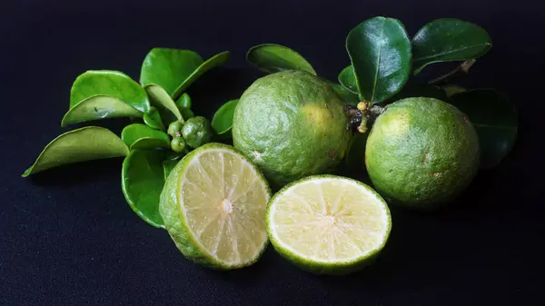 stock image Kaffir Lime or Citrus hystrix. Some are whole, some have been sliced. Focus selected, black background