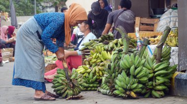 Meyve satan yaşlı bir kadın Muntilan Market 'te muz kesiyor, Magelang.