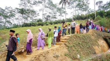 Wonosobo 'daki köylüler dini bir etkinlik için tepeden aşağı yürüyorlar.