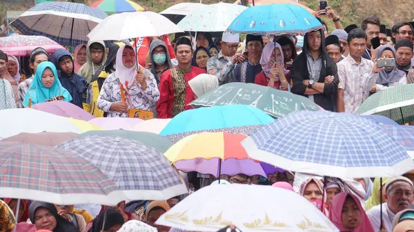Dini bir etkinlikte şemsiyeli Müslümanlar