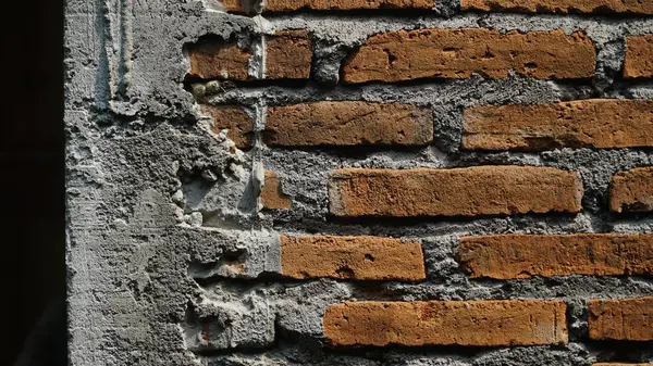 Duvarın kenarında kırmızı tuğla ve çimento var. Arkaplan tasarımı malzemesi olarak kullanılabilir
