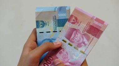 Kadınlar tarafından tutulan Endonezya rupiası banknotları, 50,000 ve 100,000 rupiah. Seçilene odaklan