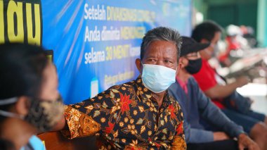 Sedayu Yogyakarta Sağlık Merkezi 'nde aşı için sırada bekleyen bir adam var.