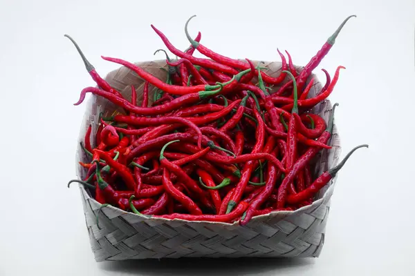 stock image Red chili pepper in a bamboo basket isolated on a white background, focus selected