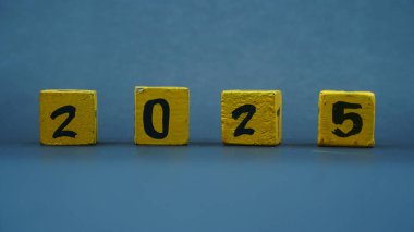 2025 sayılı tahta blok takvimi. Koyu arkaplanda sarı