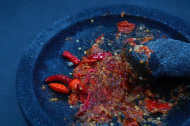 Kırmızı biber sosu, taş bir harç ve tokmak üzerinde. Koyu arkaplan, seçili odaklanma.