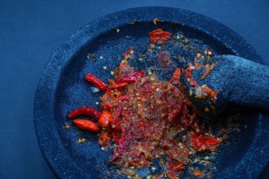 Kırmızı biber sosu, taş bir harç ve tokmak üzerinde. Koyu arkaplan, seçili odaklanma.