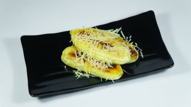 Siyah tabakta peynir dilimli kızarmış muz. Seçilene odaklan