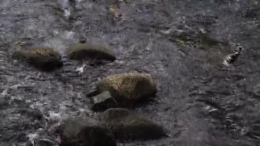 Nehirdeki su akışı, büyük ve küçük kayalar var. Üst görünüm