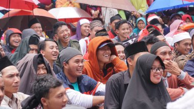 Wonosobo, İndonezya. İnsanlar dini bir etkinlikte gülümser ve tezahürat yaparlar. Cavalı yüzler. Seçilene odaklan