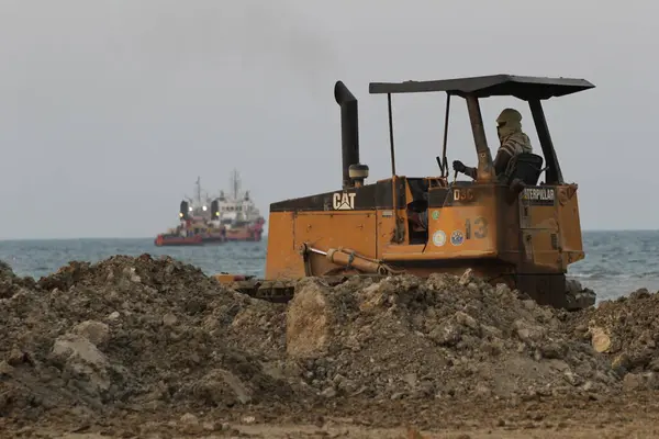 stock image Yellow excavator is leveling the ground on the beach