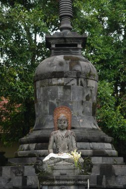 Buddha statue with stupa and leaves in the background. Focus selected clipart