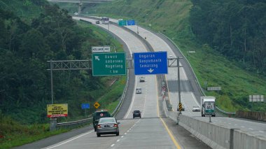 Trans Java toll road KM 443 at noon. There are signs for directions to the cities of Ambarawa, Magelang, Semarang, Ungaran, Bawen clipart